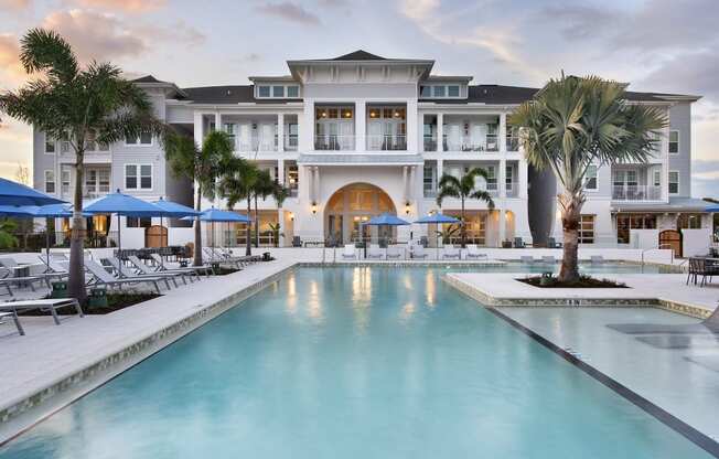 a large swimming pool with palm trees in front of a building