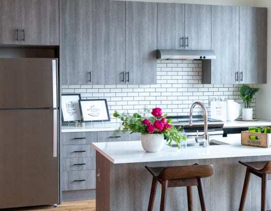 a kitchen with gray cabinets and a white tile back splash