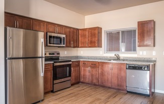 an empty kitchen with wooden cabinets and stainless steel appliances