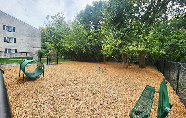 A playground with a green slide and two green benches.
