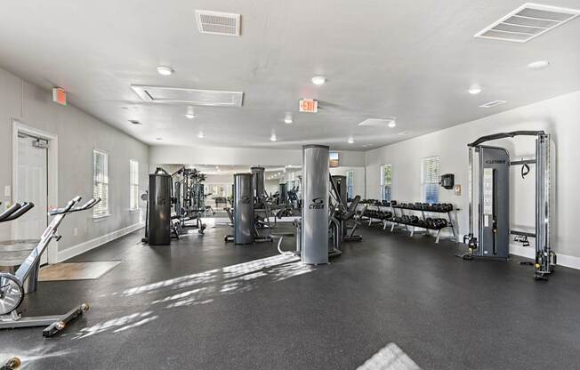 A gym with a variety of equipment including treadmills, weights, and exercise machines.