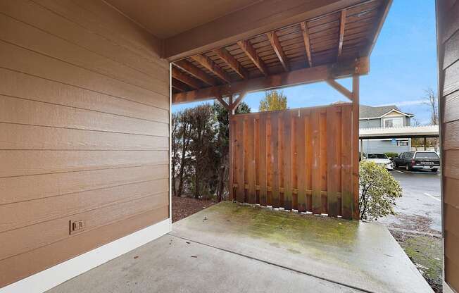 A wooden fence and a small tree are visible from a covered outdoor area.
