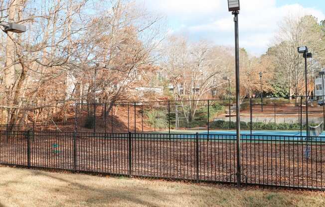 a tennis court with a fence in front of a pool