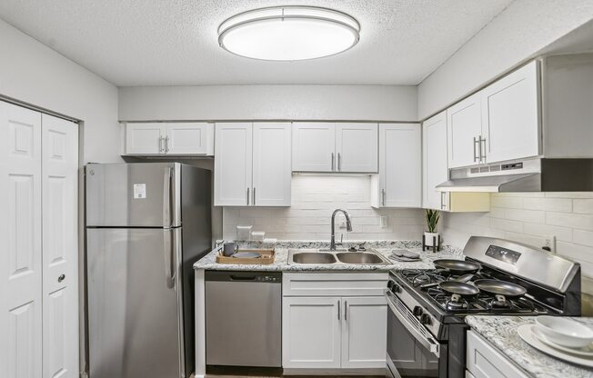 A kitchen with a refrigerator, stove, and sink.