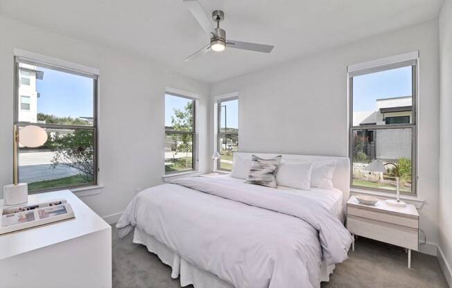 a white bedroom with a large bed and a ceiling fan