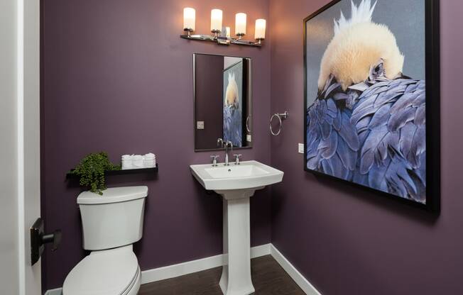 a bathroom with purple walls and a large painting on the wall