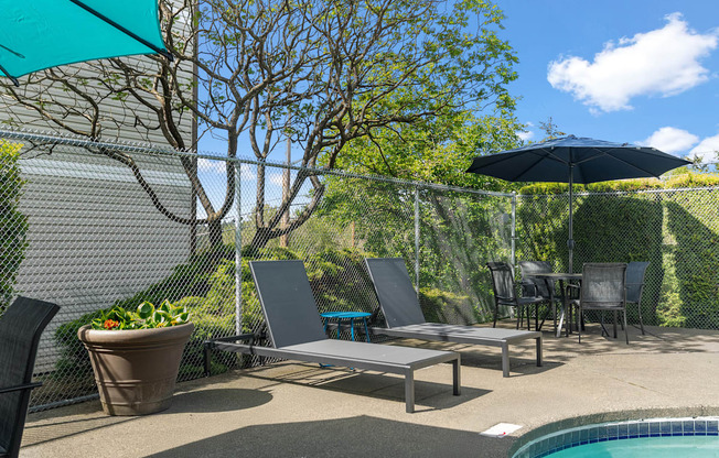 A poolside patio with a table, chairs, and a pool.