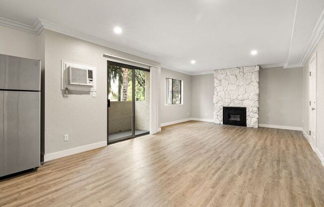 A spacious living room with wood flooring and a fireplace.
