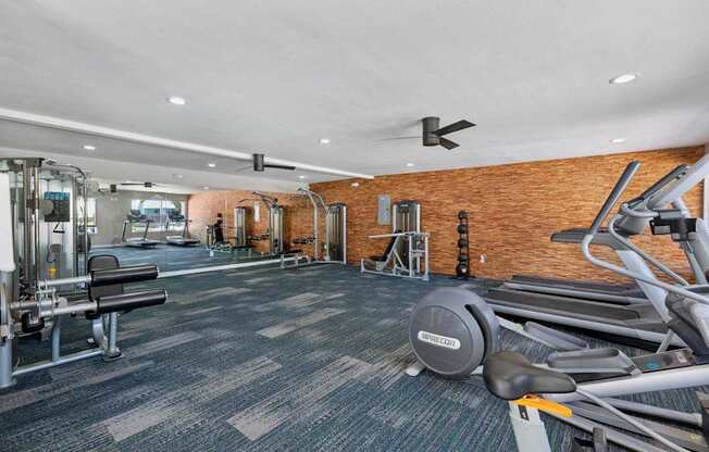 A gym with a variety of equipment including treadmills, weights, and exercise machines.