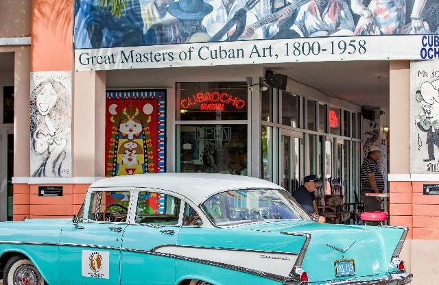 Photograph of a restaurant near our apartment in Miami, featuring a large poster with a Cuban painting and neon signs.