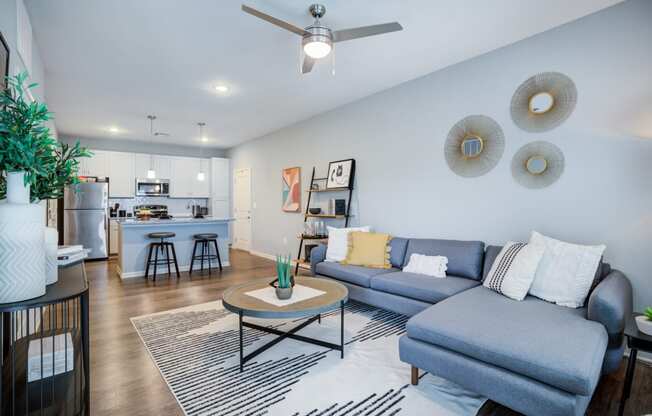 a living room with a couch coffee table and a kitchen in the background