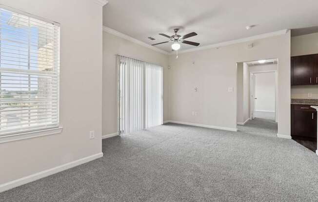 A room with a ceiling fan and carpeted floor.