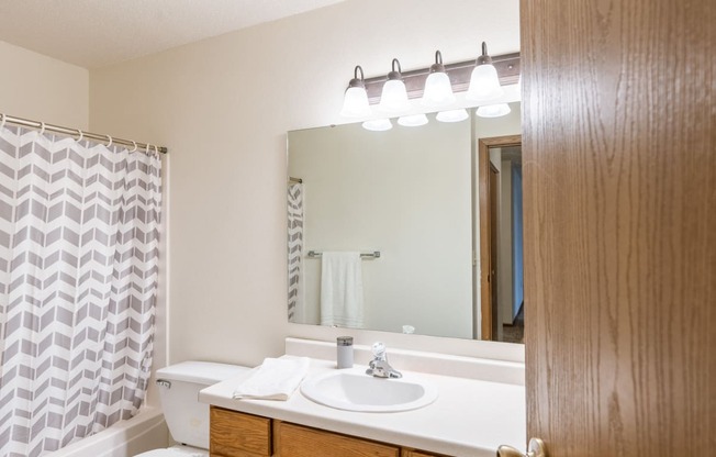 a bathroom with a sink and a mirror and a shower. Fargo, ND Country Edge Apartments