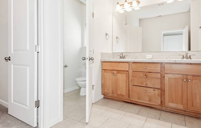A bathroom with a white door and a wooden cabinet at The Landing Apartments and Townhomes, Oregon, 97045