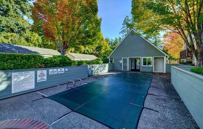 A small house with a green roof and a driveway in front.