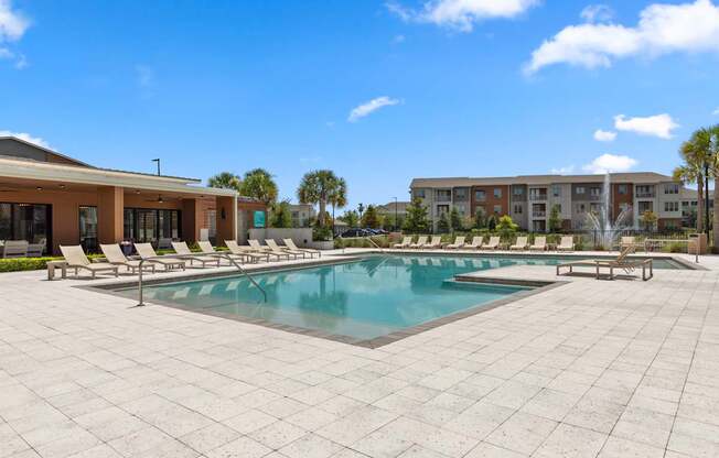 A large pool surrounded by a tiled patio and lounge chairs.
