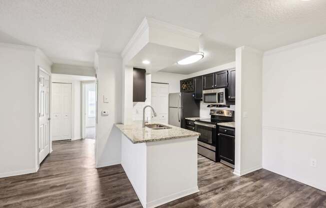 A kitchen with a white island and dark wood floors.