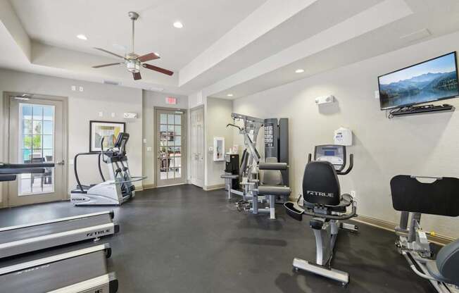 A spacious gym with treadmills, elliptical machines, and a television.