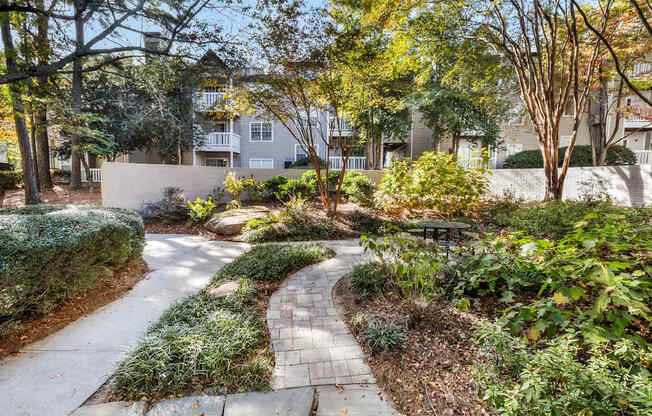 A pathway leads through a landscaped area with a building in the background.