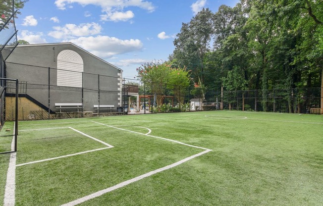 A tennis court surrounded by a fence and trees.