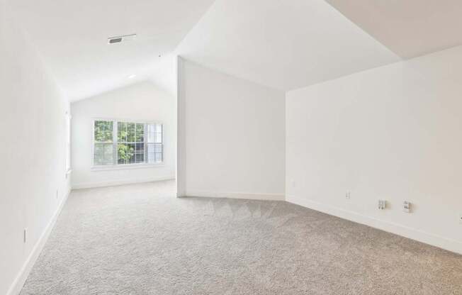 A spacious living room with a carpeted floor and a window.