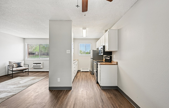 Modern kitchen with stainless steel appliances, bright living area, and elegant wood flooring