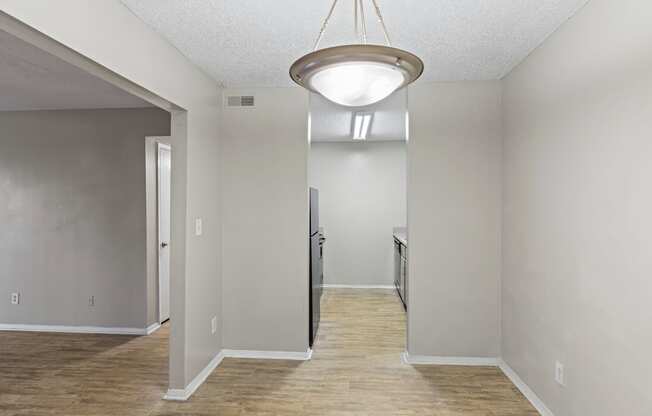 A room with a light hanging from the ceiling and a door on the left.