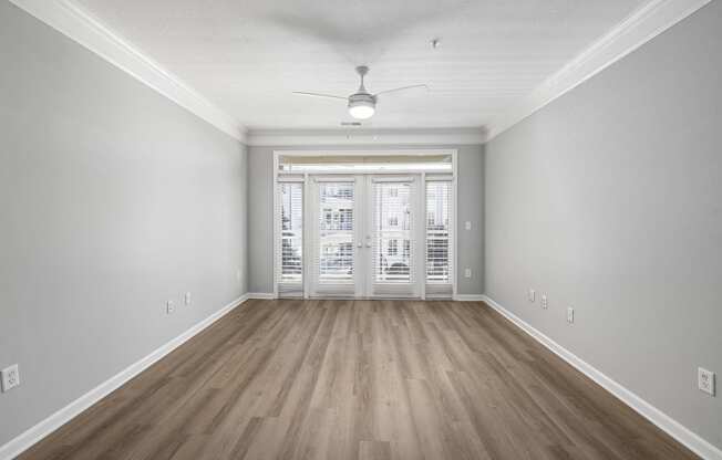 an empty living room with hardwood floors and a ceiling fan