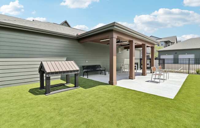 a covered patio with a picnic table and chairs in a backyard at The Depot Raymore, MO 64083