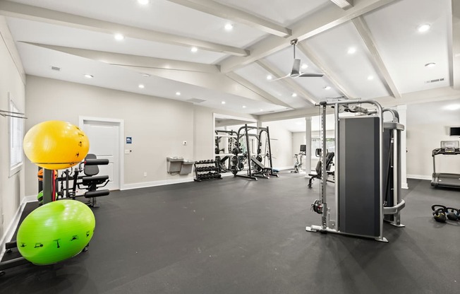 A gym with a variety of equipment including a yellow ball and a green ball.