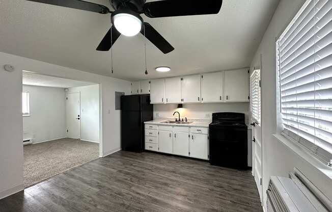 an empty kitchen and living room with a ceiling fan