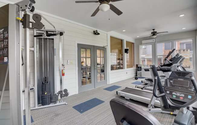 the gym has plenty of cardio equipment and glass doors to the patio
