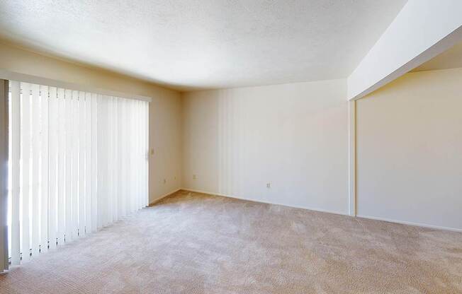 A large living room with a carpeted floor and a window with blinds at Foxwood and The Hermitage, Portage, MI