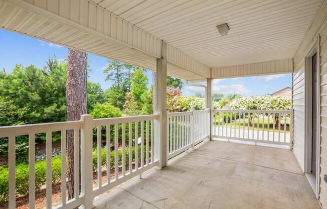a covered porch with a view of a yard and trees