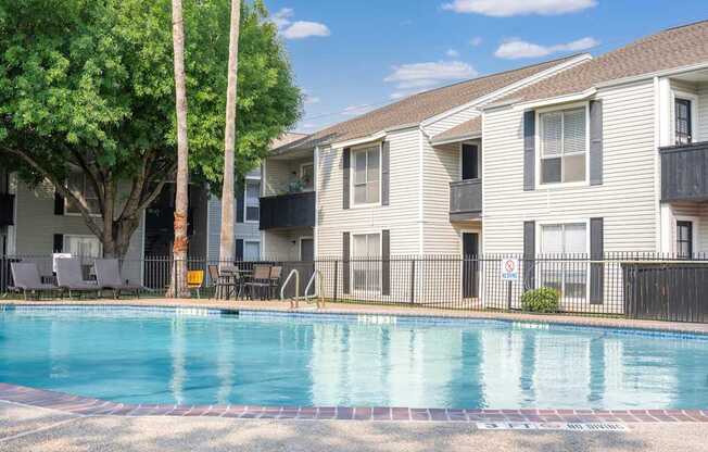 A swimming pool in front of a building with a red brick border.