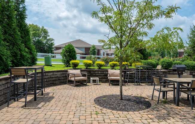a patio with tables and chairs and a tree
