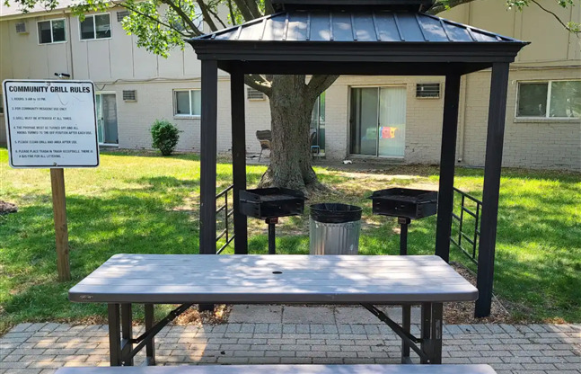 A gazebo with a canopy is surrounded by a brick patio and a sign that reads "Community Girls.".