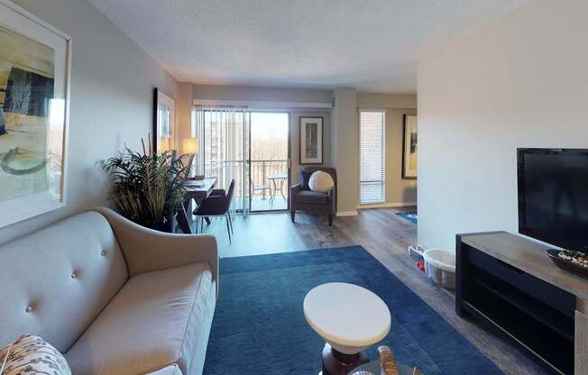 A living room with a couch, a chair, a potted plant, and a television.