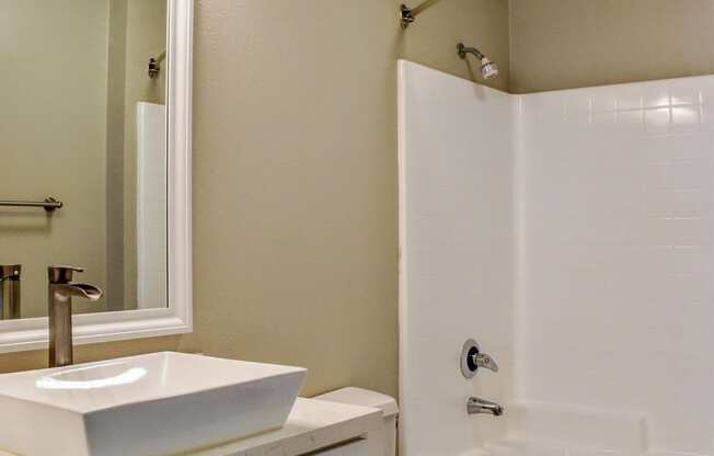 Batroom with tub, toilet, and raised vanity bowl