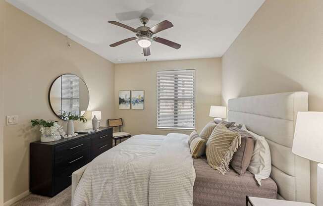 A bedroom with a large bed, a dresser, and a ceiling fan.