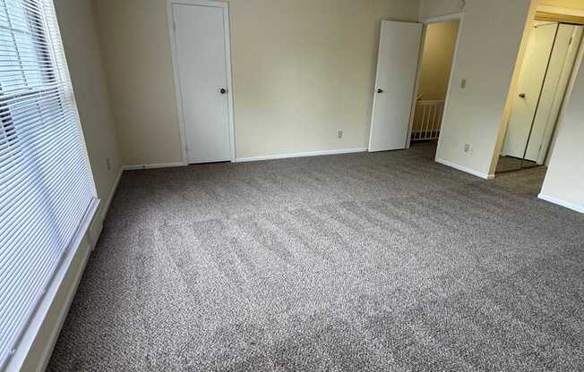 A room with a carpeted floor and three doors.