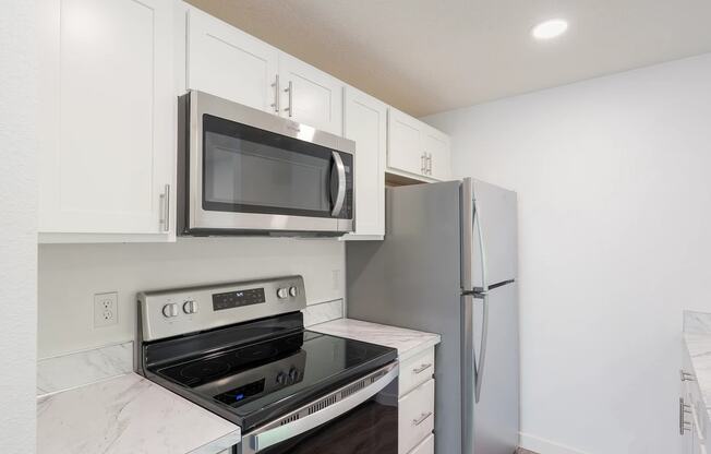 a kitchen with white cabinets and stainless steel appliances