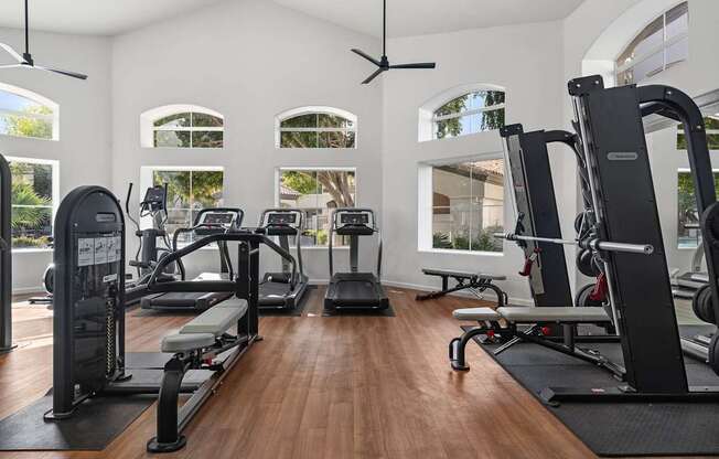 A gym with a variety of equipment including treadmills, weights, and exercise machines.