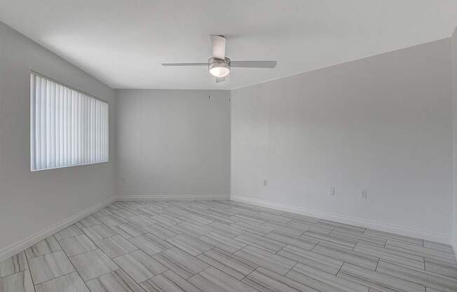 A room with a ceiling fan and a window with blinds.