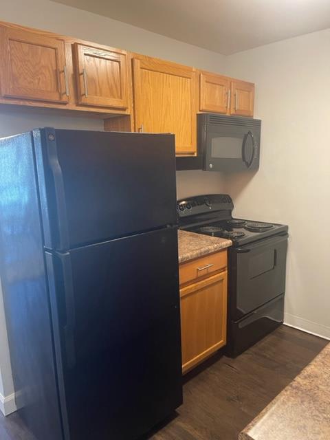 a kitchen with a black refrigerator and a stove