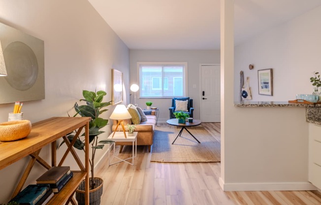 a living room with white walls and wooden floors and a dining room table