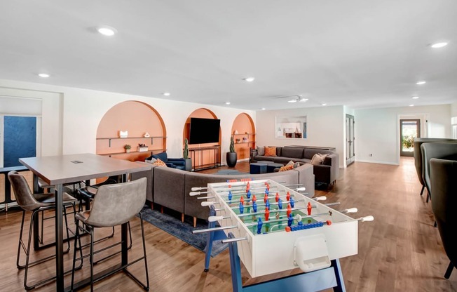a living room with a table and chairs and a game table in the middle