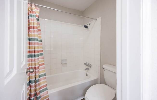 A white toilet sits next to a bathtub in a bathroom.