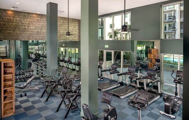 a large fitness center with cardio equipment and glass windows