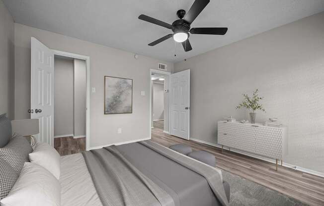 A bedroom with a bed, a ceiling fan, and a nightstand.